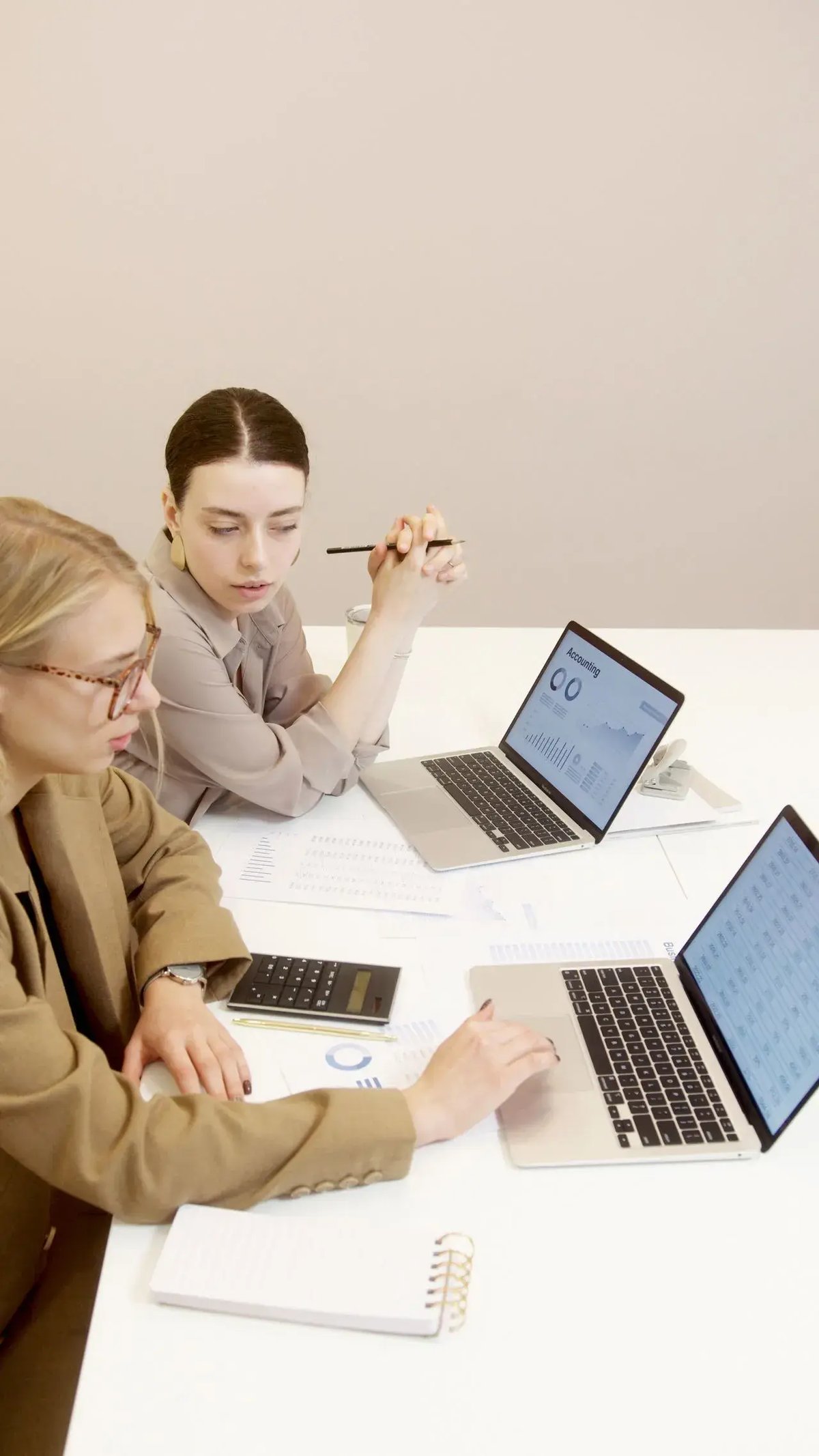two women at a desk looking at a computer screen