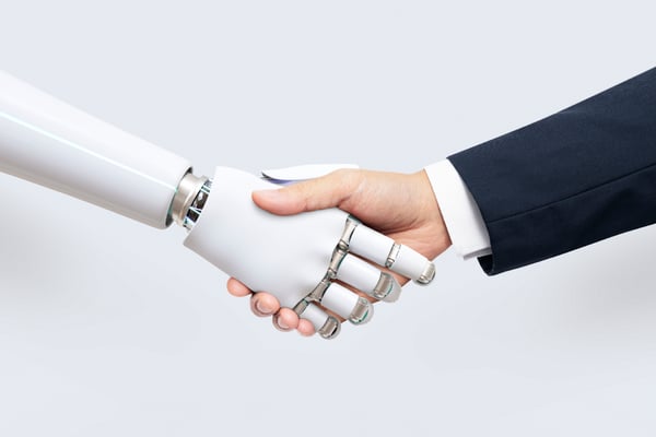 A robotic hand and a human hand shake hands.